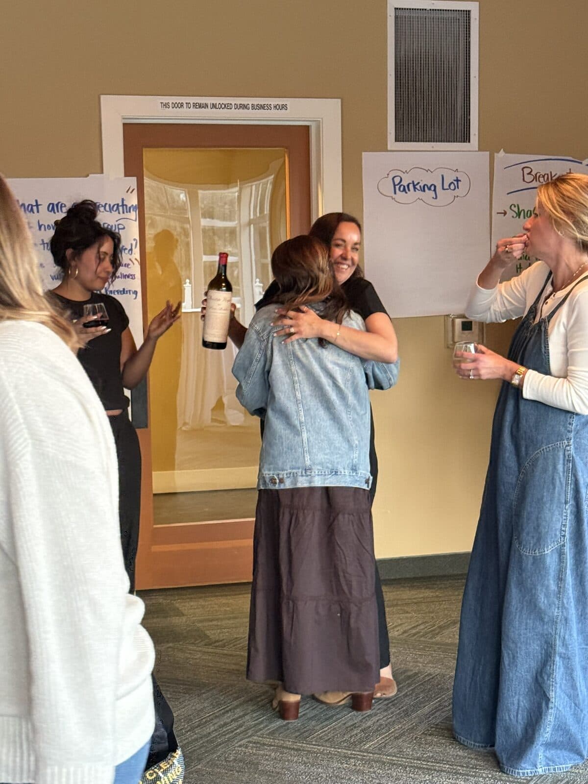 Two women hugging at the wine reception after a workshop