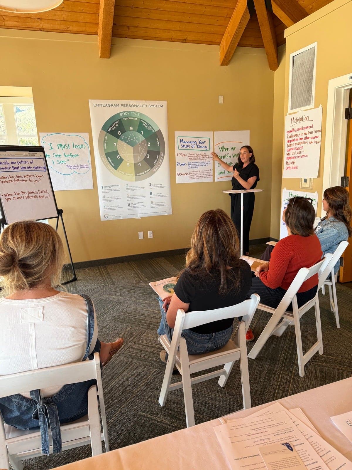Katie presenting beside a large Enneagram Personality System poster, participants watching from their seats